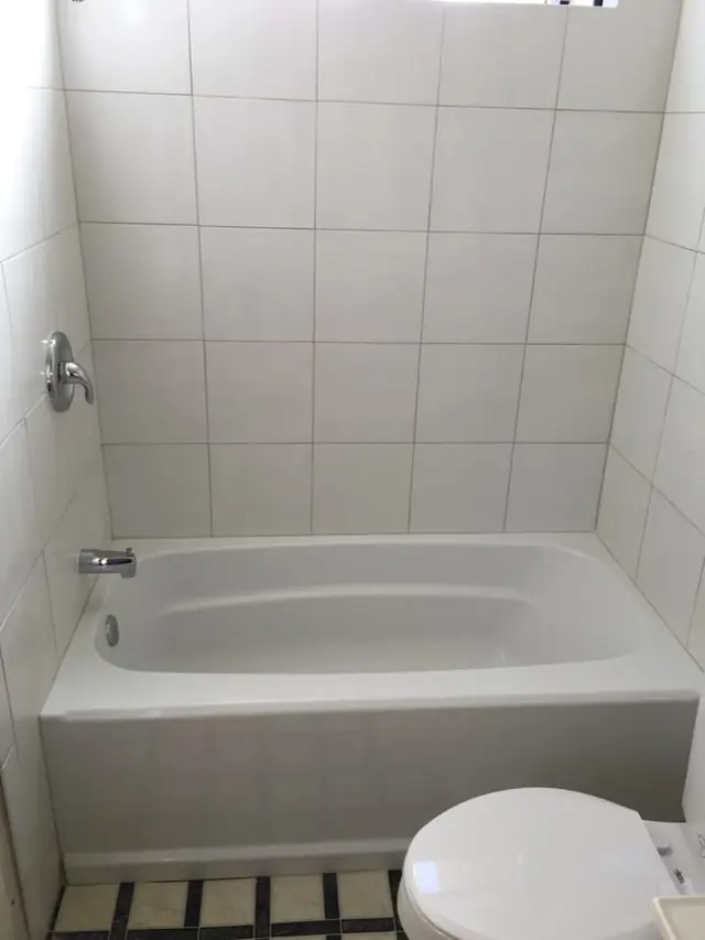 New bathtub with white tile walls
