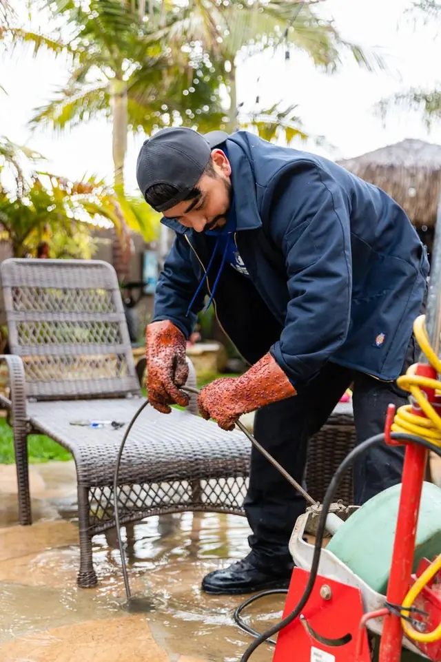 Technician running a drain machine on a backyard patio
