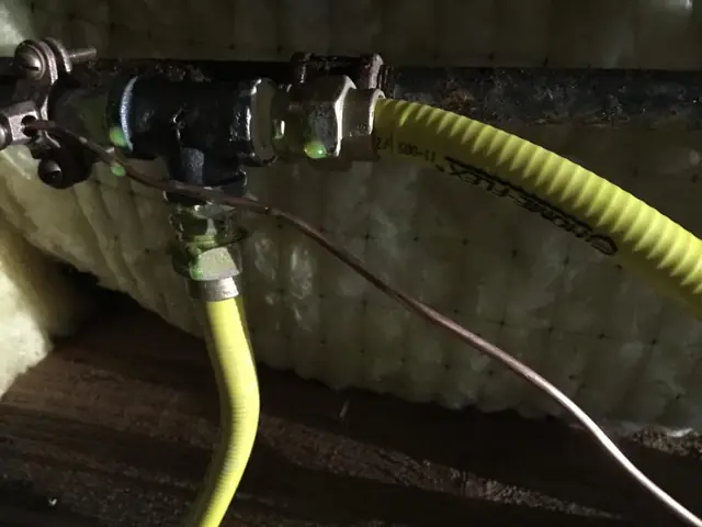 Yellow flex gas line tapped into a black iron gas pipe