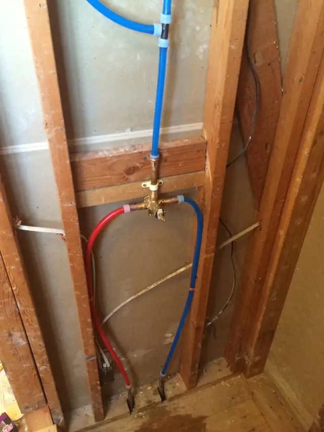 Red and blue PEX water lines run inside an open wall