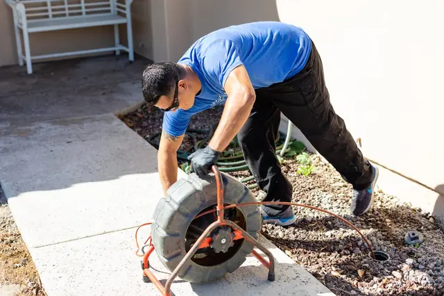 Technician feeding a rooter cable at a residence