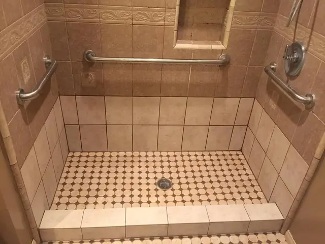 Tiled walk-in shower with grab bars where a bathtub used to be