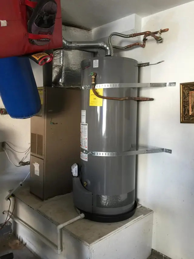 New tank water heater installed in a garage with strapping and venting